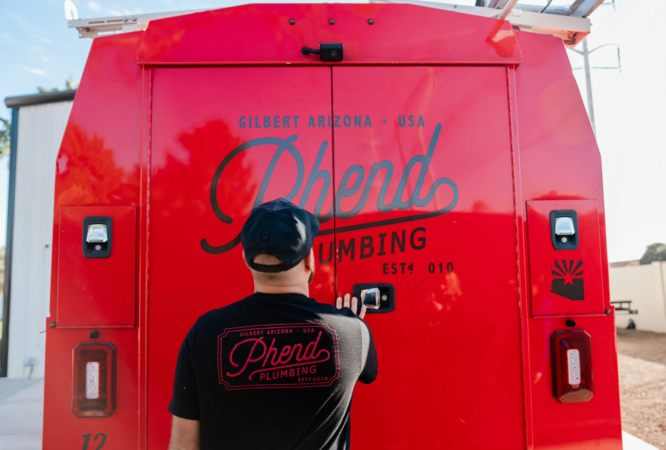 Phend Plumbing technician at the back of a red branded service van