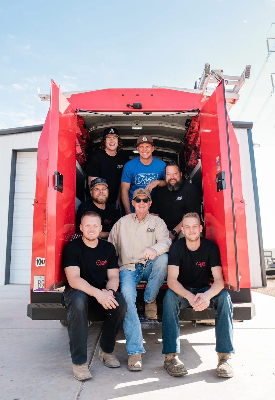 The Phend Plumbing crew in the back of an open red service van